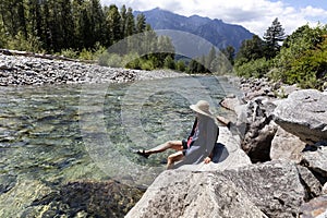 Mature woman kicking her feet into the cool river water during a summer time