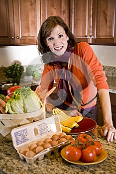 Mature woman in kitchen with fresh produce