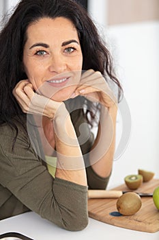 mature woman with kiwis on chopping board