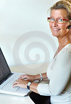 Mature woman, laptop and headset for call centre, company and remote work for telemarketing. Desk, internet and crm for