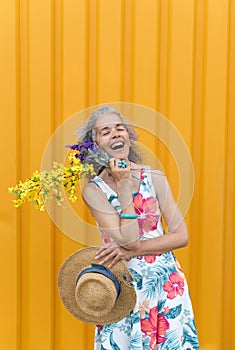 Mature woman laughing eyes shut Flowers Yellow background