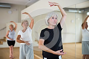 Mature woman learning classical ballet technique in choreography class