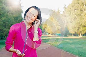 Mature woman listen music before or after jog in the park photo
