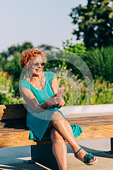 Mature woman listening to the music on her smartphone in the park
