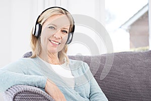 Mature Woman Listening To Music On Wireless Headphones