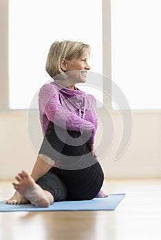 Mature Woman Looking Away While Doing Stretching Exercise