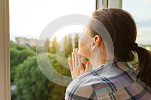 Mature woman looking out the window, close-up view from the back