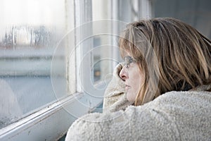 Mature woman looking out the window on a rainy day