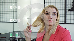 Mature woman looking upset examining her hair with split ends