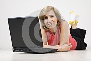 Mature woman lying on floor using laptop