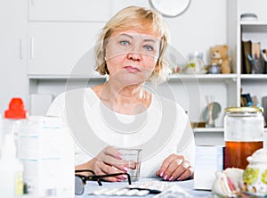 Mature woman with medicines and bills