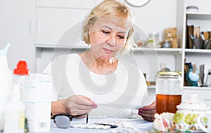 Mature woman with medicines and bills