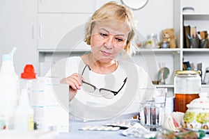 Mature woman with medicines and bills