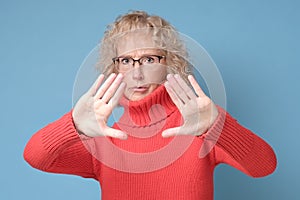 Mature woman moving away hands palms showing refusal and denial gesture