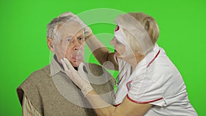 Mature woman nurse doctor examines senior patient man with problems