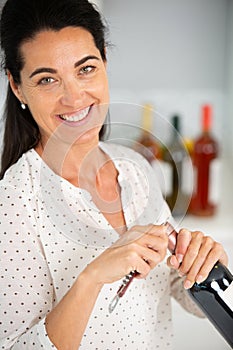 mature woman opening bottle wine