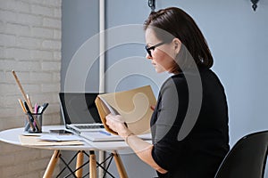 Mature woman opening envelope with paper documents