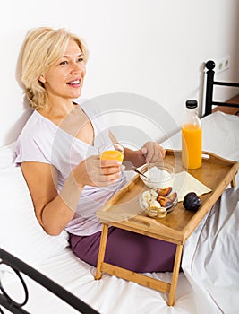 Mature woman with orange juice, berries and yogurt