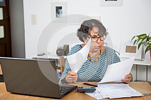 Mature woman paying bills with laptop at home