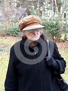 A mature woman in a peaked cap and with glasses