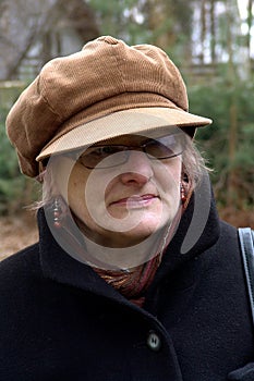 A mature woman in a peaked cap and with glasses