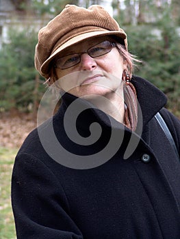 A mature woman in a peaked cap and with glasses