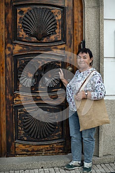 Mature woman pilgrim at the door with symbols of the Way of Santiago.