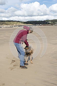 Mature woman playing with her Alsatian dog