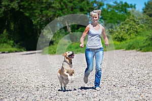 Mature woman plays with a dog at riverbanks