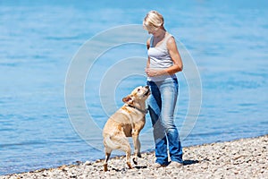 Mature woman plays with a dog riverside