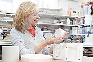 Mature Woman In Pottery Studio Casting Mug