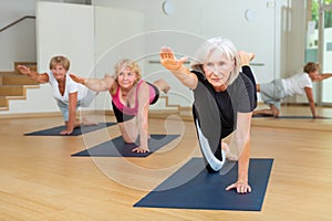 Mature woman practicing Dandayamna Bharmanasana during group yoga workout