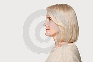 Mature woman profile view studio portrait isolated on gray background