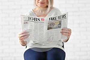 Mature woman reading newspaper on blurred background