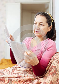 Mature woman reads newspaper