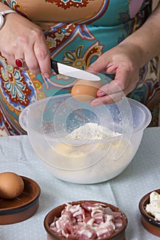 Mature woman reaking egg in bowl