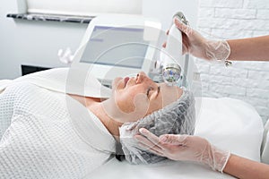Mature woman receiving laser treatment in cosmetology clinic
