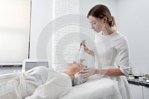 Mature woman receiving laser treatment in cosmetology clinic