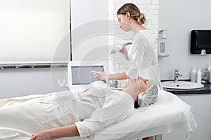 Mature woman receiving laser treatment in cosmetology clinic