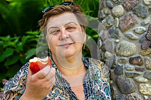 Mature woman in the Park and eating a red Apple
