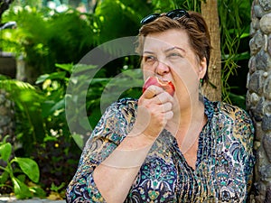 Mature woman resting and eating a red Apple