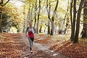 Mature Woman Running Through Autumn Woodland