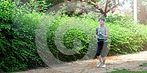 Mature woman running in the park in summer morning