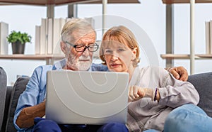 Mature woman and senior man using laptop in living room, Portrait of Worried senior couple checking their bills and work on