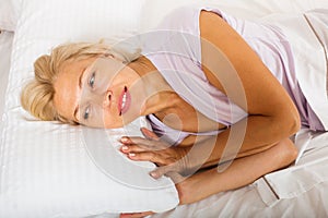 Mature woman in shirt laying on bed at bedroom