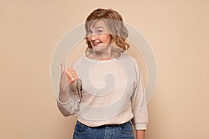 Mature woman showing aside with finger to copy space place