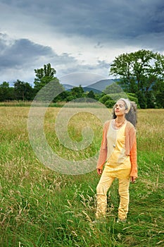 Mature woman shut eyes enjoying nature fields trees