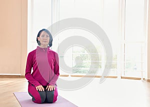 Mature woman sit on the mat on the knees