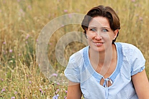 Mature woman is sitting in a flower field in summer photo