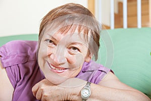 Mature woman sitting on sofa and smiling